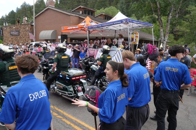 Explorers in party hats hold stick horses as the Sheriff's motor unit rides past the announcer stand