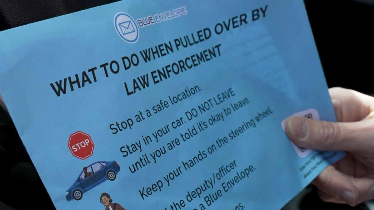 Close-up of the Blue Envelope card showing instructions: stop at a safe location, stay in your car, keep your hands on the steering wheel, tell the deputy you have a Blue Envelope