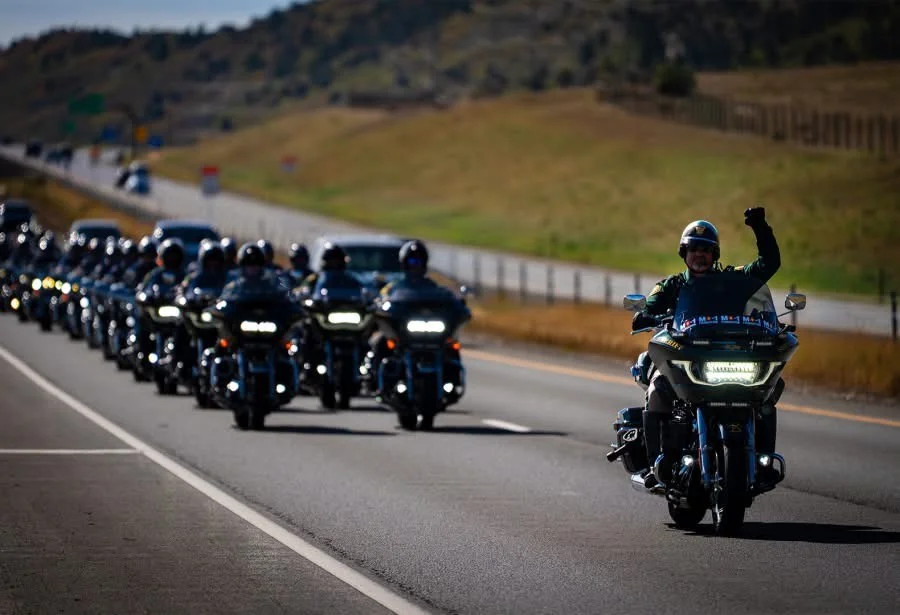 JCSO Deputy Mark Miller raising a fist as he leads a long column of motorcycles down a highway during the MC-1 Foundation Honor Run
